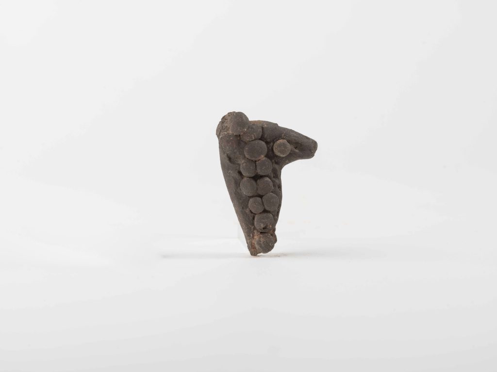 Fragment of a terracotta figurine with a bunch of grapes